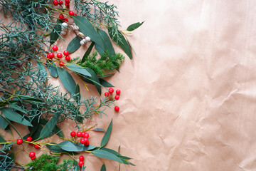 Winter green and red berry composition on craft paper. Winter natural decoration background.