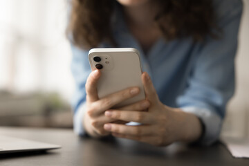 Close up view of unrecognizable woman using smartphone for browsing social media platforms, chatting with friends through messaging apps, watching videos on streaming services, playing mobile games