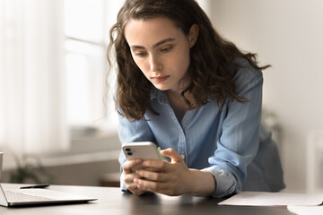 Serious woman lean at workplace desk using modern gadget, distracted from work or study on laptop,...