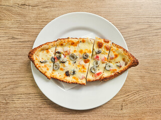 Delicious Turkish sesame bagel pizza made of cheddar cheese, tomato and olives on a table. Snack or breakfast concept.