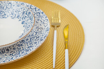 A white soup plate with a blue pattern on the edges stands on a blue-and-white patterned serving...