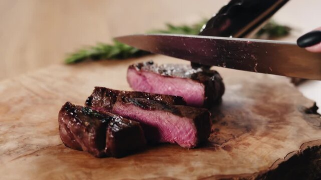 Slow motion slide slicing medium rare fillet mignon steak on wood board