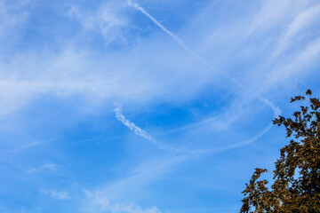 Blue sky with light feathery clouds and the contrails of aeroplanes