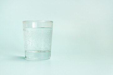 Transparent glass cup with clean sparkling water on light blue background