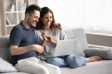 Happy wife and husband using laptop at home, make video call to family using application, watching...