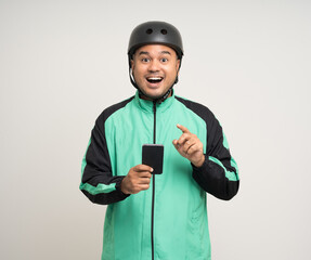 Young asian rider wearing green jacket uniform and bike helmet standing holding smartphone food application on isolated. Male delivery service worker. Delivery courier and shipping food service.