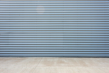 Exterior of a gray corrugated metal factory building  facade with concrete floor.