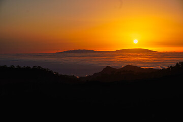 Tenerife. Canary Islands. Sunset over the sea of ​​clouds. The skies are dyed red and the clouds look like bronze. In the background the silhouette of La Palma