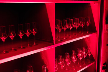 Shelf with Numerous Glasses Illuminated by Red Light