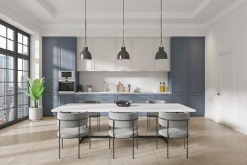 White and blue home kitchen interior with dinner table and cabinet, window