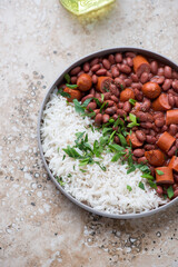 Red beans, sausage and white rice, vertical shot on a beige granite background, high angle view