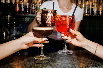 Girls celebrating with cocktails aperol spritz, Moscow mule, coffee spritz, close view in a bar