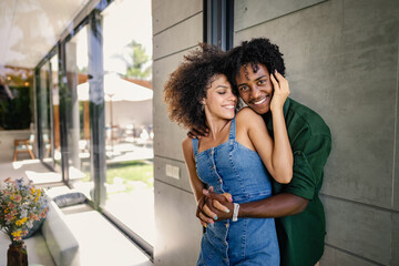 Naklejka premium Portrait of a young cheerful couple of African descent standing in a modern luxury villa, having an intimate moment of love and affection. Exotic and luxury travel concept.