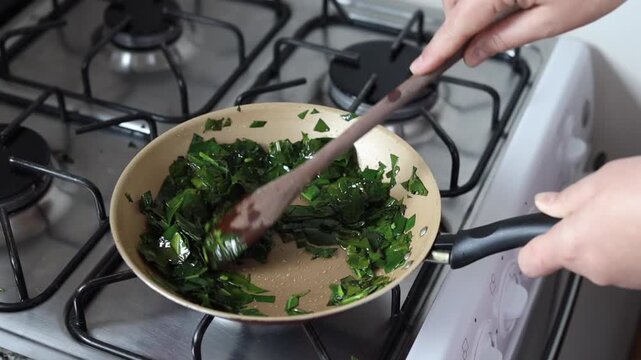 Hands cooking ora-pro-nobis (Pereskia aculeata) in a frying pan, a popular edible plant in Brazil