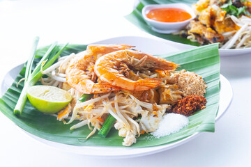 Pad Thai with fresh shrimp, a popular Thai food, Place the plate with banana leaves on a white plate, isolate and white background, close up, selective focus