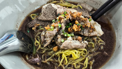 Boat noodles in a pink bowl on a wooden table