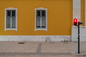Red pedestrian traffic light with stationary indication on the right side of the frame and building...