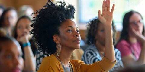 african woman in a classroom setting raises her hand to ask a question or participate in a discussion.