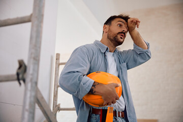 Manual worker feeling exhausted after working at construction site.