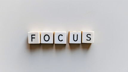 white Scrabble tiles arranged to spell out the word "FOCUS" against a neutral background