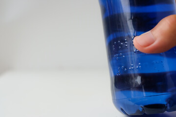 Braille font on a plastic water bottle. Raised dots on the plastic bottle. Person reads Braille. Read with fingers. Braille printing for plastic packaging. Accessibility for Persons with Disabilities.