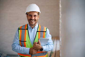 Fototapeta premium Happy building contractor with touchpad at construction site looking at camera.