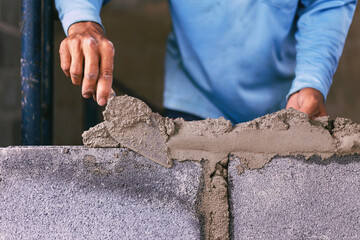 Construction workers are building cement walls with brick blocks.
