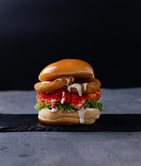 Gourmet meat burger with cheese and veggies. Juicy delicious hamburger on darkmood picture for restaurant decoration, poster.
