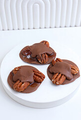 Chocolate covered walnut. Delicious nutritious nut candies falling into a rotating wooden bowl