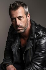 Obraz premium Man in Black Leather Jacket Posing Against Neutral Background