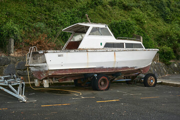old pleasure boat on an old rusty trailer with flat tires