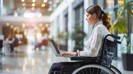 Businesswoman in a wheelchair working on a laptop in a brightly lit office. Focus on accessibility and professional inclusion.