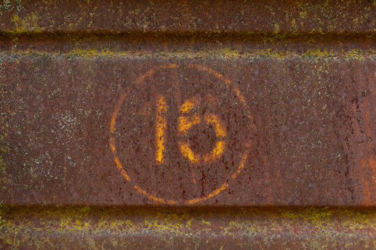 rusty metal plate or sign with number 16 (sixteen)
