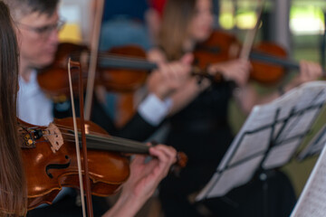 Close-up of a professional violinist of a symphony orchestra playing on the stage of a classical theater during a musical concert. Performers play music for the audience