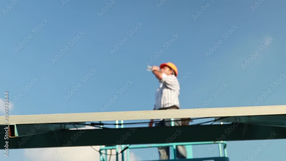 Wall mural Blurred Senior male engineer wearing safety helmet drinking water aerial work platform inspecting solar panel systems safety with electric drill tools install solar panels on very high structures.