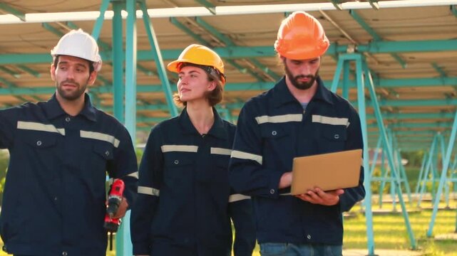 Team of electrical engineers men and women working in solar panel power station join hands and high five showing good standing at successful maintenance.