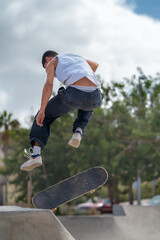 young man skater jumping a ramp in a skate park. vertical composition