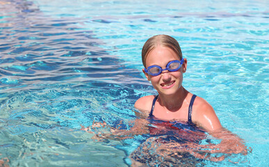 A girl in swimming glasses swims in a pool at a resort on a summer sunny day. Summer travel hotel vacation or classes