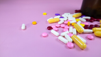 Colourful pills and Pills and medicine bottles  placed on a pink background. Assorted pharmatheutical multicolored medicinal capsules and pills. Healthcare and medical concept, space for text.
