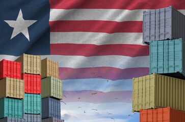 Liberia flag and big stack of shipping cargo containers in docks with sky background close up