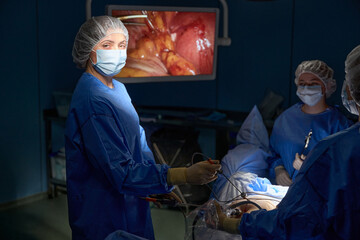 Female surgeons doing laparoscopic surgery, with big monitor on the background