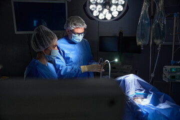 Doctors during gynecological surgery operation using laparoscopic equipment in hospital