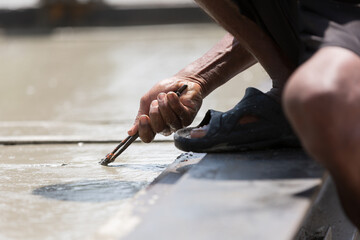 Construction worker using pincer plier cutting steel binding wire wet concrete at construction work...