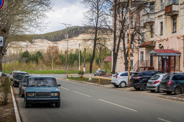 The city streets of Zhigulevsk, a city in Samara oblast of Russia, with Soviet style building, cars and Zhiguli mountains around.
