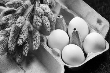 Chicken eggs in a cardboard box and dry flowers