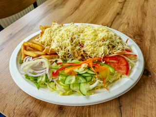 Kebab with fries and cheese on a plate.