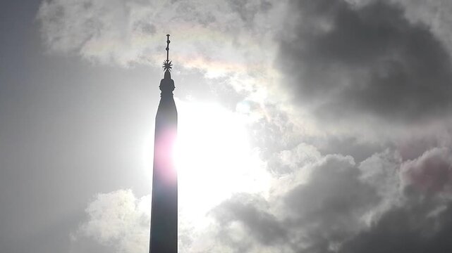 Ancient Egyptian obelisk Flaminio in Rome in Italy, sky with sun, bird in flight  and moving clouds Iridescence, Irisation. Topics: weather, optical phenomenon, history, art, tourism