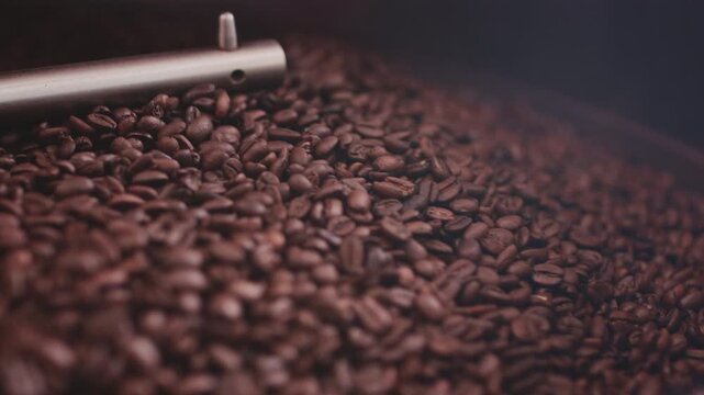 Macro close up: Coffee seeds or beans in a roasting machine, mixing aroma beans. Preparation fresh aroma caffeine on manufacturing warehouse. Production of fresh fried coffee