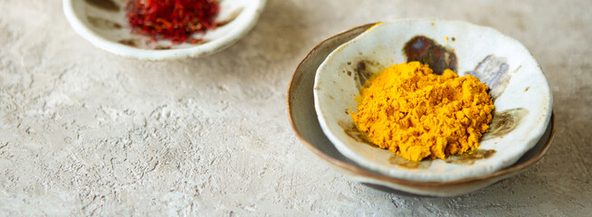 ceramic bowls with turmeric powder and saffron on a light table, top view, space for text
