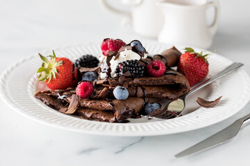 Delicious chocolate crepes topped with whipped cream and berries.